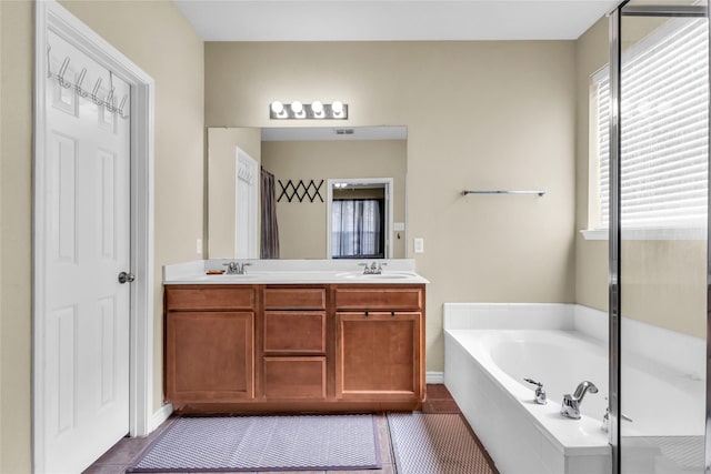 full bath featuring a bath, double vanity, a sink, and tile patterned floors