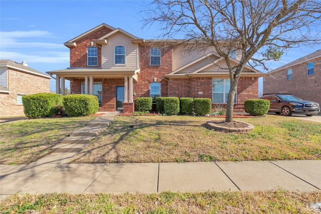 traditional home featuring a front yard and brick siding