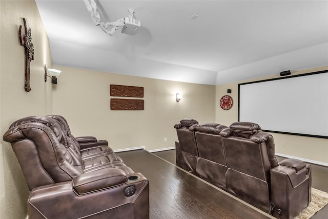 home theater room featuring lofted ceiling, baseboards, and wood finished floors