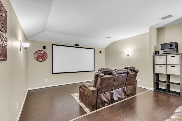 cinema room with lofted ceiling, baseboards, visible vents, and wood finished floors