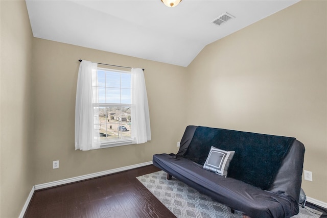 living area featuring vaulted ceiling, wood finished floors, visible vents, and baseboards