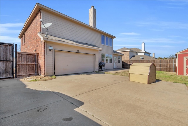 view of front of house with driveway, a chimney, an attached garage, fence, and brick siding