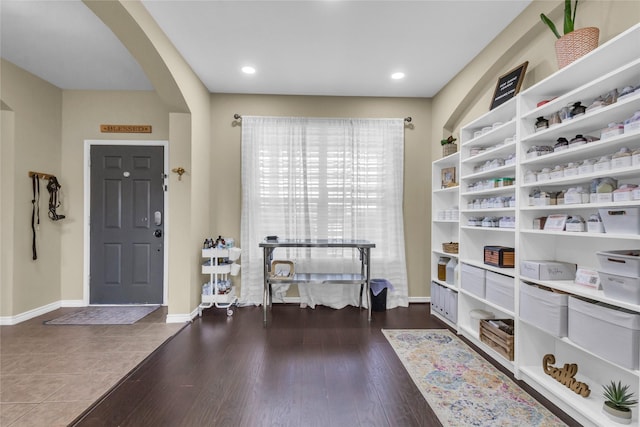 foyer entrance with baseboards, arched walkways, dark wood-type flooring, and recessed lighting