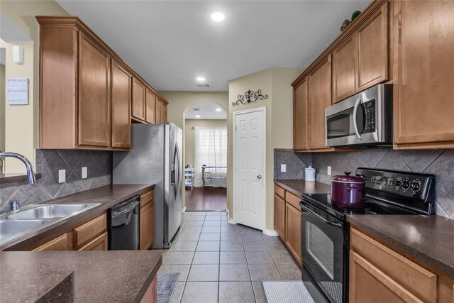 kitchen featuring a sink, visible vents, black dishwasher, decorative backsplash, and dark countertops