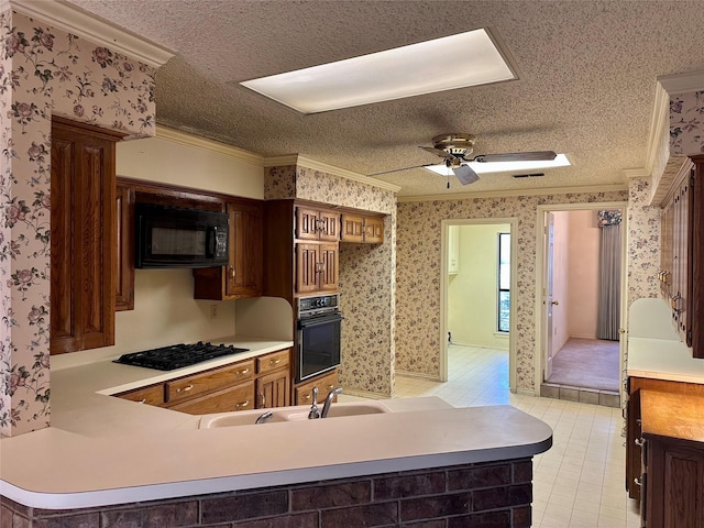 kitchen with crown molding, light countertops, a peninsula, black appliances, and wallpapered walls