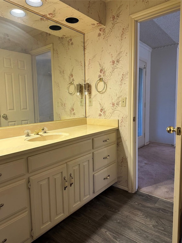 bathroom featuring wood finished floors, vanity, and wallpapered walls