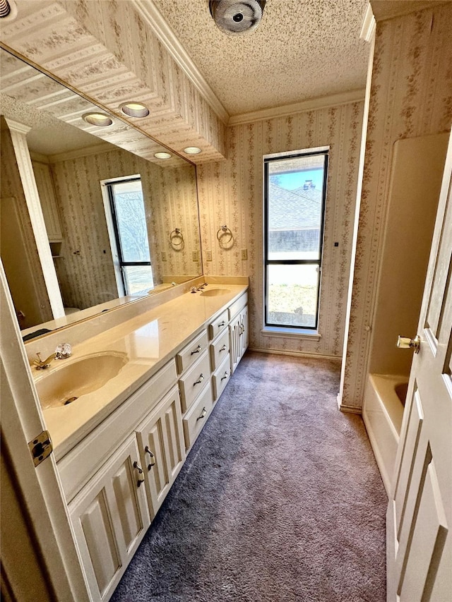 bathroom with wallpapered walls, a sink, and carpet flooring