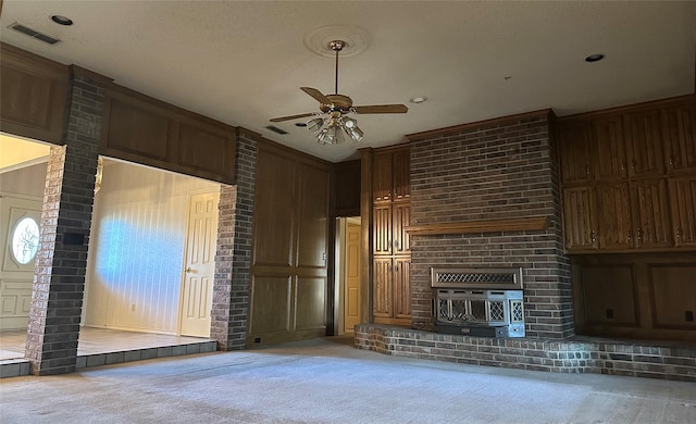 unfurnished living room with visible vents, a decorative wall, carpet flooring, ceiling fan, and a textured ceiling