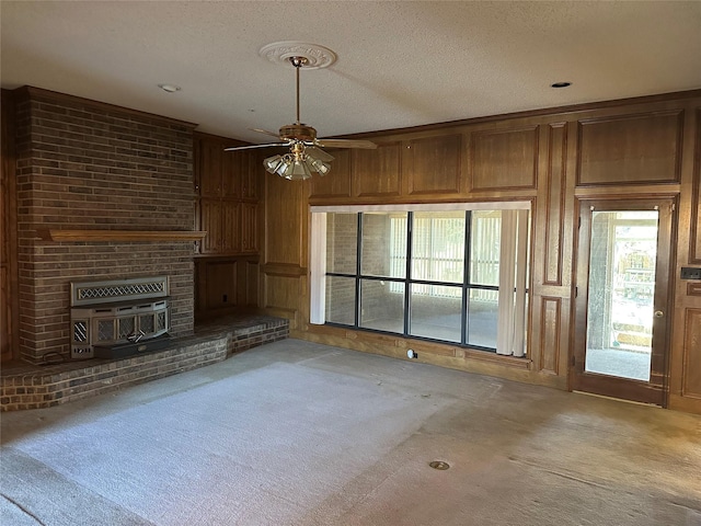 unfurnished living room featuring light carpet, ceiling fan, wooden walls, and a textured ceiling