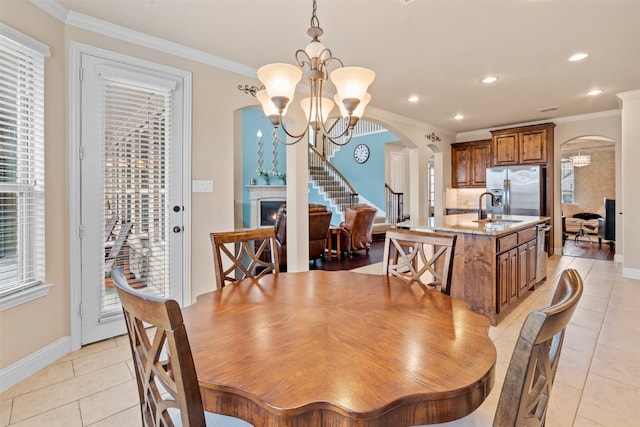 dining space featuring an inviting chandelier, arched walkways, light tile patterned floors, and crown molding