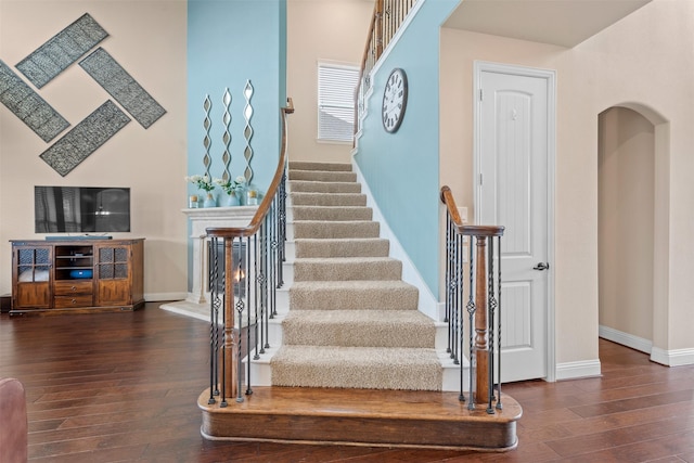 stairs with baseboards, arched walkways, and hardwood / wood-style floors