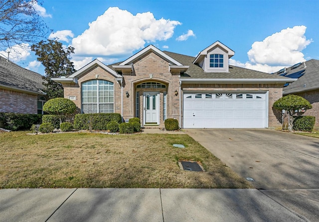 view of front facade with a garage, driveway, a front lawn, and brick siding