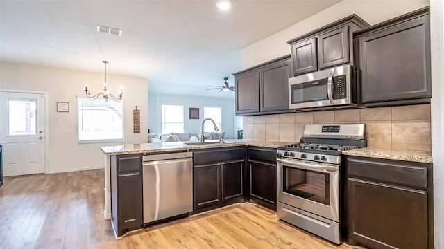 kitchen with light stone counters, a peninsula, visible vents, appliances with stainless steel finishes, and tasteful backsplash