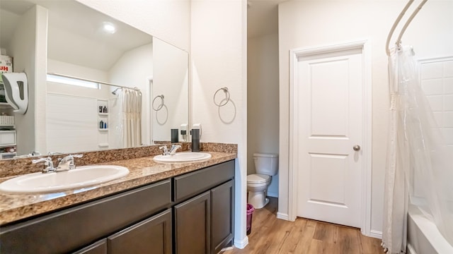 bathroom with toilet, double vanity, a sink, and wood finished floors