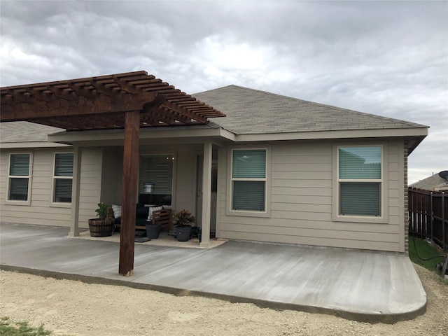 back of property featuring a shingled roof, a patio area, fence, and a pergola