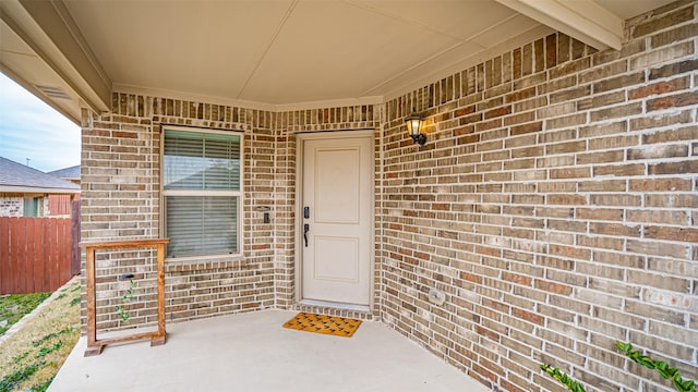 entrance to property featuring brick siding and fence