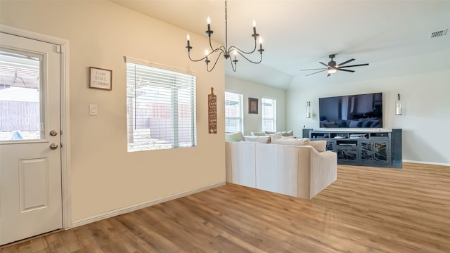 unfurnished living room featuring lofted ceiling, visible vents, wood finished floors, baseboards, and ceiling fan with notable chandelier