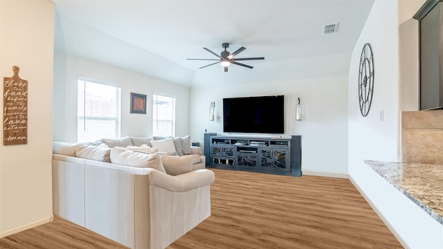 living area with baseboards, visible vents, a ceiling fan, lofted ceiling, and wood finished floors