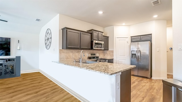 kitchen featuring light wood-style flooring, a sink, visible vents, appliances with stainless steel finishes, and decorative backsplash