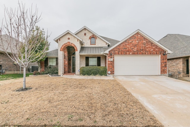 view of front of home with driveway, an attached garage, a standing seam roof, central air condition unit, and brick siding