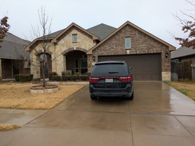 view of front of property featuring a garage, brick siding, concrete driveway, stone siding, and roof with shingles