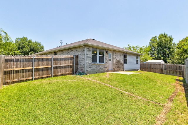 rear view of property with a fenced backyard, a lawn, and brick siding