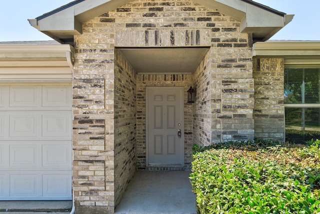 doorway to property with stone siding, brick siding, and an attached garage