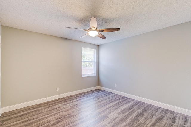 empty room featuring ceiling fan, a textured ceiling, baseboards, and wood finished floors