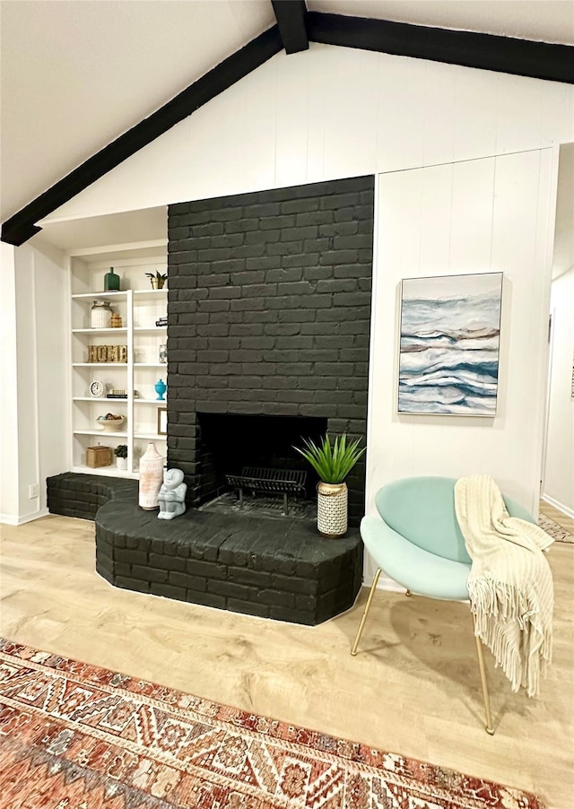 living area with lofted ceiling with beams, a fireplace, wood finished floors, and built in features