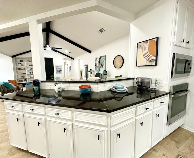 kitchen with lofted ceiling with beams, visible vents, white cabinetry, appliances with stainless steel finishes, and light wood finished floors