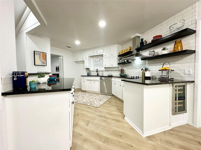 kitchen with light wood-style flooring, white cabinets, stainless steel dishwasher, open shelves, and dark countertops