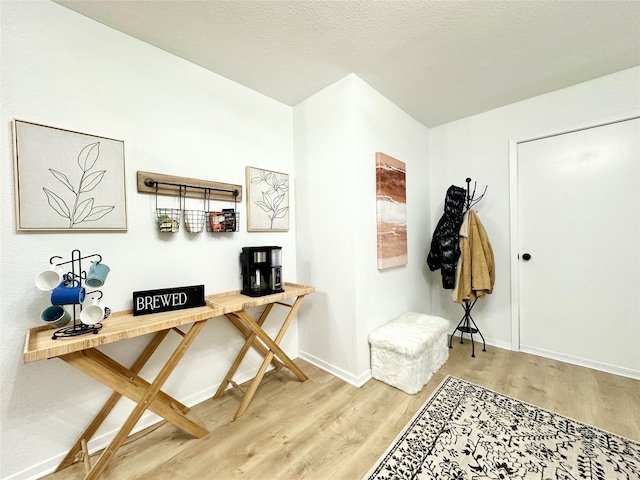 interior space with a textured ceiling, baseboards, and wood finished floors