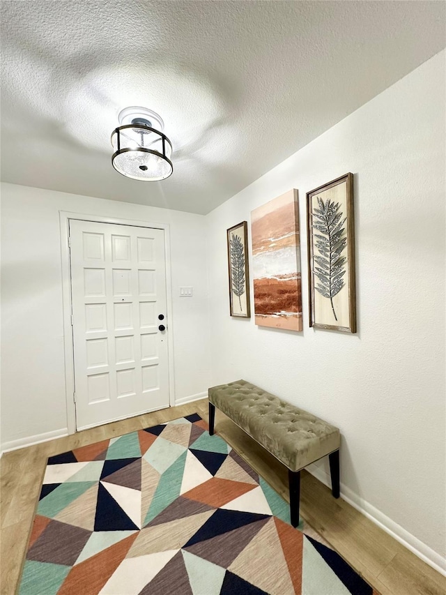 entryway featuring a textured ceiling, baseboards, and wood finished floors