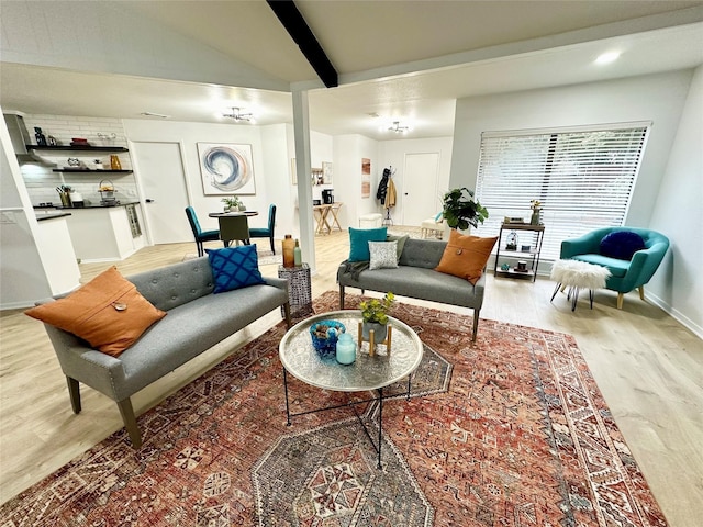 living room with vaulted ceiling with beams, light wood-style floors, and baseboards