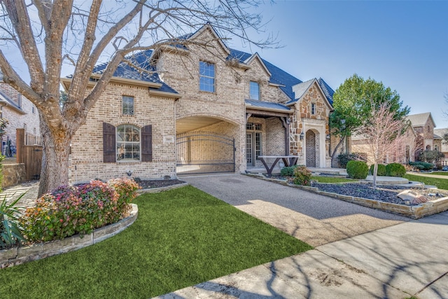 view of front facade featuring brick siding, a front yard, a standing seam roof, fence, and driveway