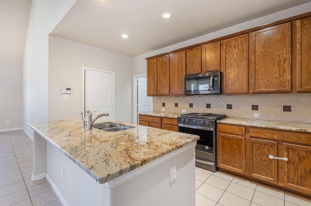 kitchen with stainless steel appliances, brown cabinets, a center island with sink, and a sink