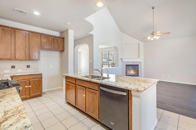 kitchen featuring visible vents, brown cabinetry, open floor plan, a sink, and dishwasher