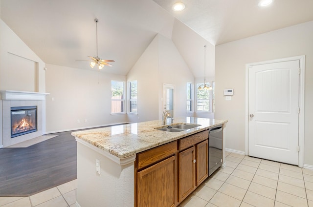 kitchen with a kitchen island with sink, a sink, open floor plan, brown cabinets, and dishwasher