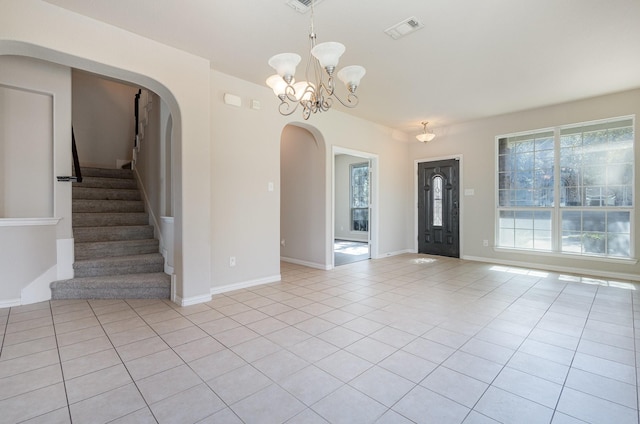 foyer entrance with arched walkways, a chandelier, light tile patterned flooring, visible vents, and stairs