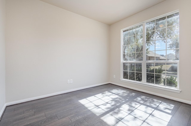 unfurnished room featuring baseboards and dark wood-type flooring