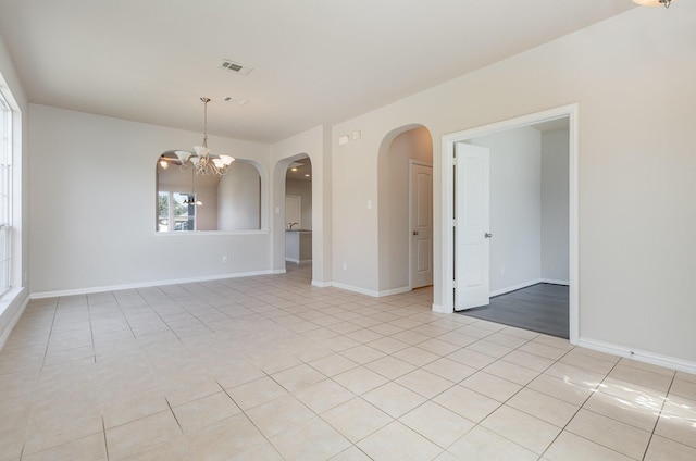 empty room featuring arched walkways, light tile patterned flooring, a notable chandelier, visible vents, and baseboards