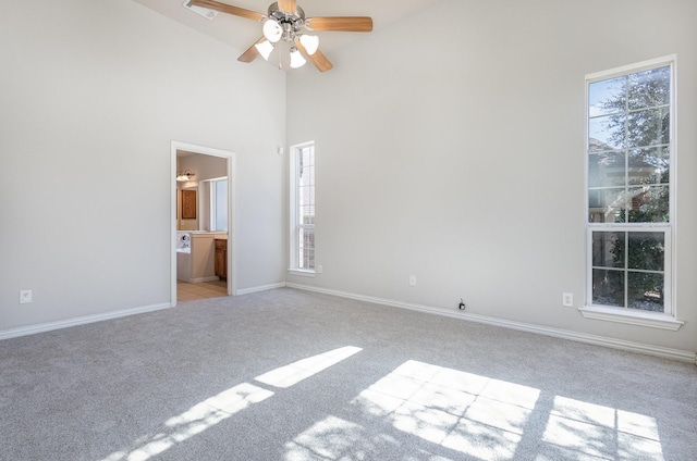 unfurnished bedroom with baseboards, a high ceiling, connected bathroom, and light colored carpet