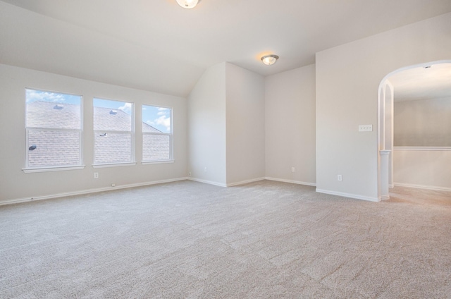 unfurnished room with light carpet, baseboards, and arched walkways