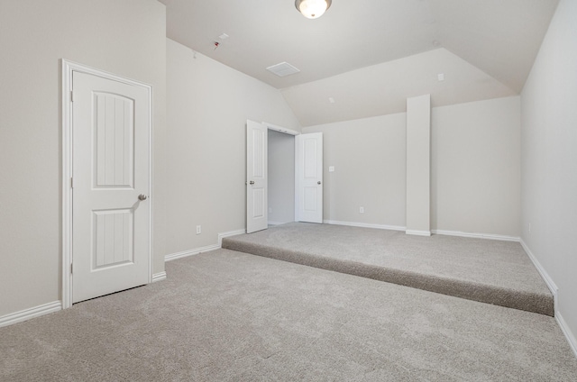 empty room with lofted ceiling, light carpet, and baseboards