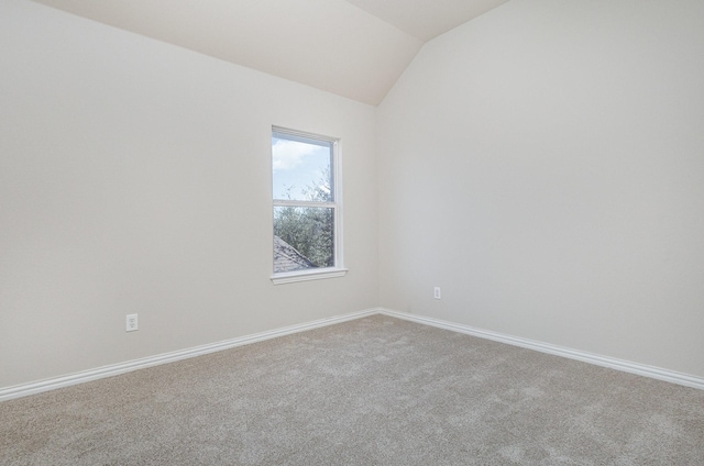 empty room with lofted ceiling, carpet floors, and baseboards