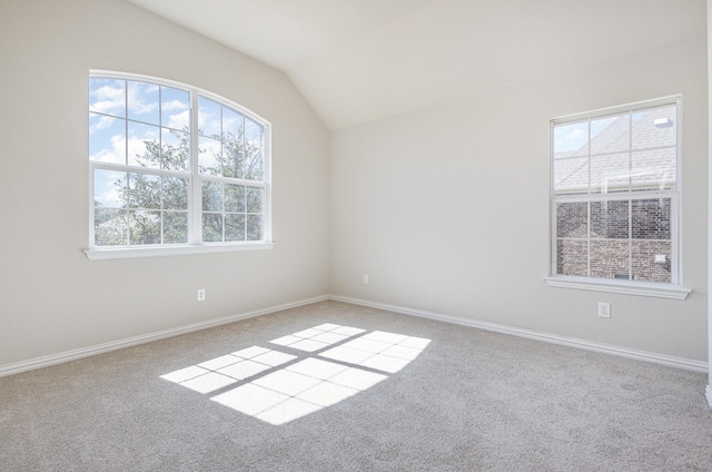 unfurnished room featuring light carpet, baseboards, vaulted ceiling, and a wealth of natural light