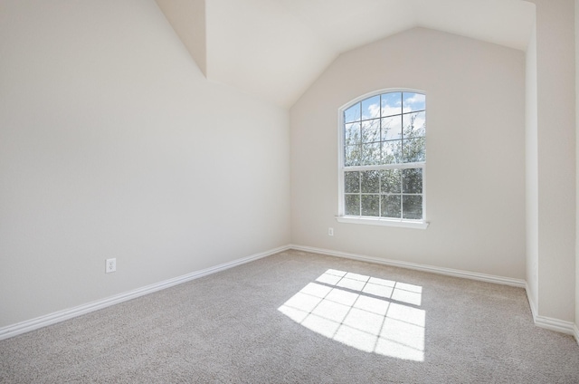 unfurnished room with lofted ceiling, light carpet, and baseboards