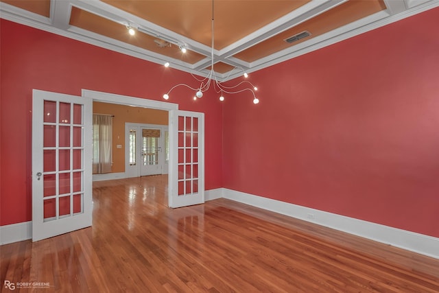 empty room featuring baseboards, visible vents, coffered ceiling, wood finished floors, and french doors