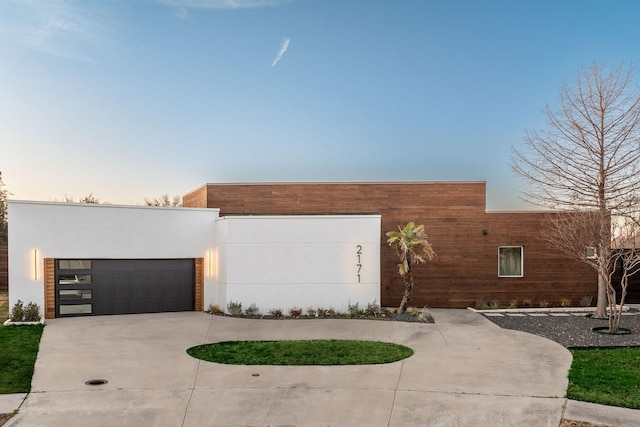 contemporary house with driveway, a garage, and stucco siding