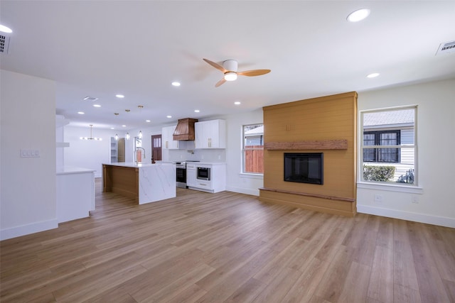 unfurnished living room with light wood-type flooring, ceiling fan, baseboards, and recessed lighting